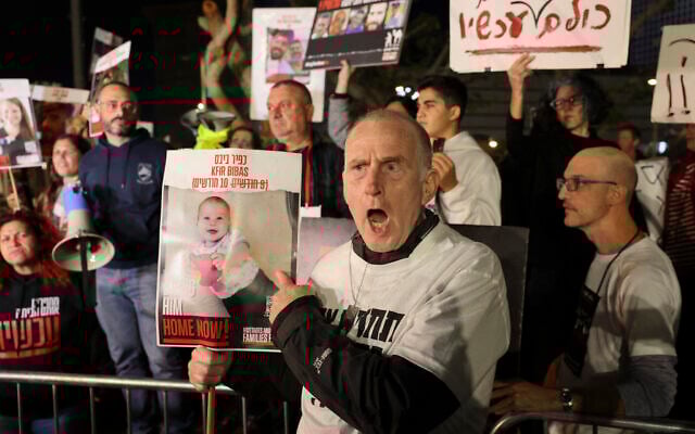 A man holds a portrait of 10-month-old Kfir Bibas, held by Palestinian terrorists together with others since the October 7 assault, as families and supporters hold a demonstration outside the Ministry of Defense in Tel Aviv on December 15, 2023. (Ahmad Gharabli/AFP) A man holds a portrait of 10-month-old Kfir Bibas, held by Palestinian terrorists together with others since the October 7 assault, as families and supporters hold a demonstration outside the Ministry of Defense in Tel Aviv on December 15, 2023. (Ahmad Gharabli/AFP)