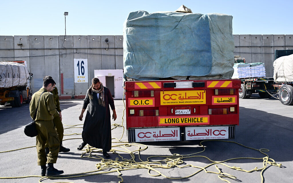 Israeli soldiers inspect humanitarian aid trucks arriving from Egypt on the Israeli side of the Kerem Shalom border crossing with the southern Gaza Strip, on December 22, 2023, amid the ongoing war between Israel and the Palestinian terror group Hamas. (Alberto Pizzoli/AFP)