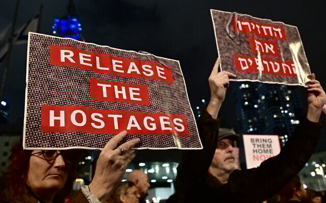 Protesters lift placards during a rally for supporters and relatives of Israeli hostages who have been held by terrorists in Gaza since October 7, in Tel Aviv on December 23, 2023. (Alberto PIZZOLI / AFP) Protesters lift placards during a rally for supporters and relatives of Israeli hostages who have been held by terrorists in Gaza since October 7, in Tel Aviv on December 23, 2023. (Alberto PIZZOLI / AFP)