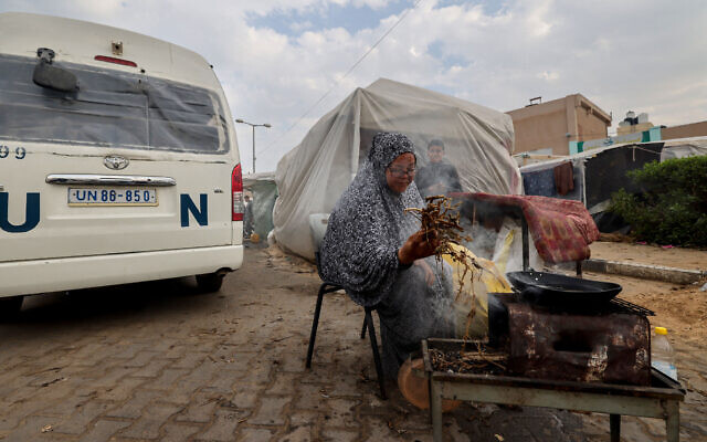 A displaced Palestinian woman lights a cooking fire outside a tent in Rafah in the southern Gaza Strip on December 27, 2023, amid the ongoing war between Israel and the Palestinian terror group Hamas. (Mohammed Abed/AFP)
