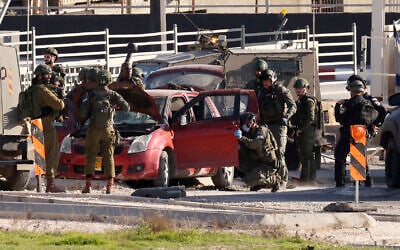 Israeli security forces surround a car which was used by a Palestinian to ram into a group of Israelis at the entrance of al-Fawwar refugee camp, south of Hebron in the West Bank, on December 30, 2023. (Hazem Bader/AFP)