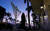 A woman walks past a menorah standing outside a Jewish synagogue ahead of the start of Hanukkah, in Miami Beach, Florida, December 1, 2023. (Rebecca Blackwell/AP)