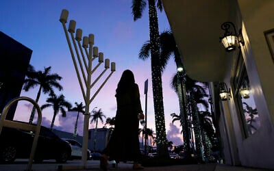 A woman walks past a menorah standing outside a Jewish synagogue ahead of the start of Hanukkah, in Miami Beach, Florida, December 1, 2023. (Rebecca Blackwell/AP)