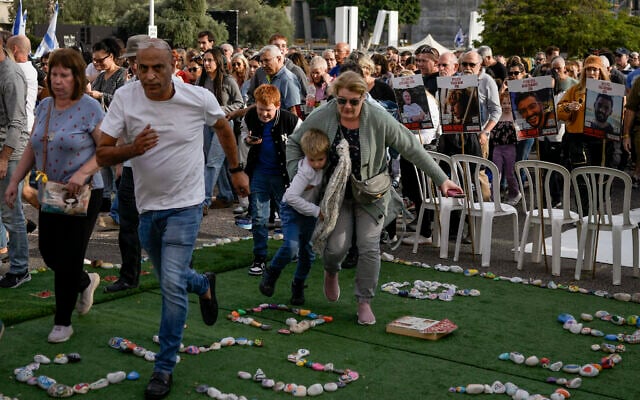 Israelis campaigning for the release of the hostages held in Gaza rush to a shelter as a siren sounds a warning of incoming rockets fired from the Gaza Strip, in Tel Aviv, Dec. 8, 2023. (AP Photo/Leo Correa)