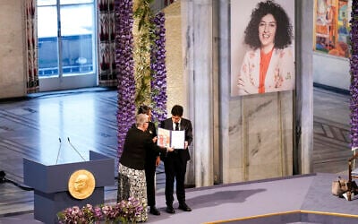 Leader of the Nobel Committee Berit Reiss-Andersen presents the Nobel Peace Prize for 2023 to Ali, right, and Kiana Rahmani, for their mother, imprisoned Iranian activist Narges Mohammadi, in Oslo City Hall, Oslo, Norway, December 10, 2023. (Fredrik Varfjell/NTB via AP)