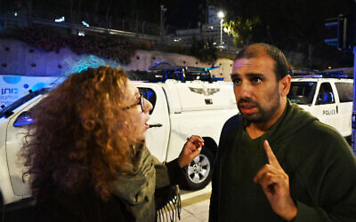 Eyal Lahiani, right, speaks at a rally in Tel Aviv, Israel on December 16, 2023 with a demonstrator at another rally in favor of a prisoner exchange deal with Hamas. (Canaan Lidor/Times of Israel)