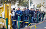 Illustrative: Palestinian workers line up at the entrance to the Jewish settlement of Ma’aleh Adumim, February 23, 2023. (Erik Marmor/Flash90)