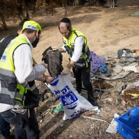 Zaka personnel collect clothes that belong to the victims of the October 7 Hamas massacre, near the Israel-Gaza border, southern Israel, November 19, 2023. (Chaim Goldberg/Flash90)