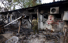 Soldiers walking next to the destruction by Hamas terrorists in Kibbutz Nir Oz on October 7, 2023, in southern Israel, November 21, 2023. (Chaim Goldberg/Flash90)
