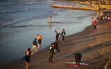 Surfers at the sea in Jaffa on sunset, on November 21, 2023. (Jamal Awad/ Flash90)