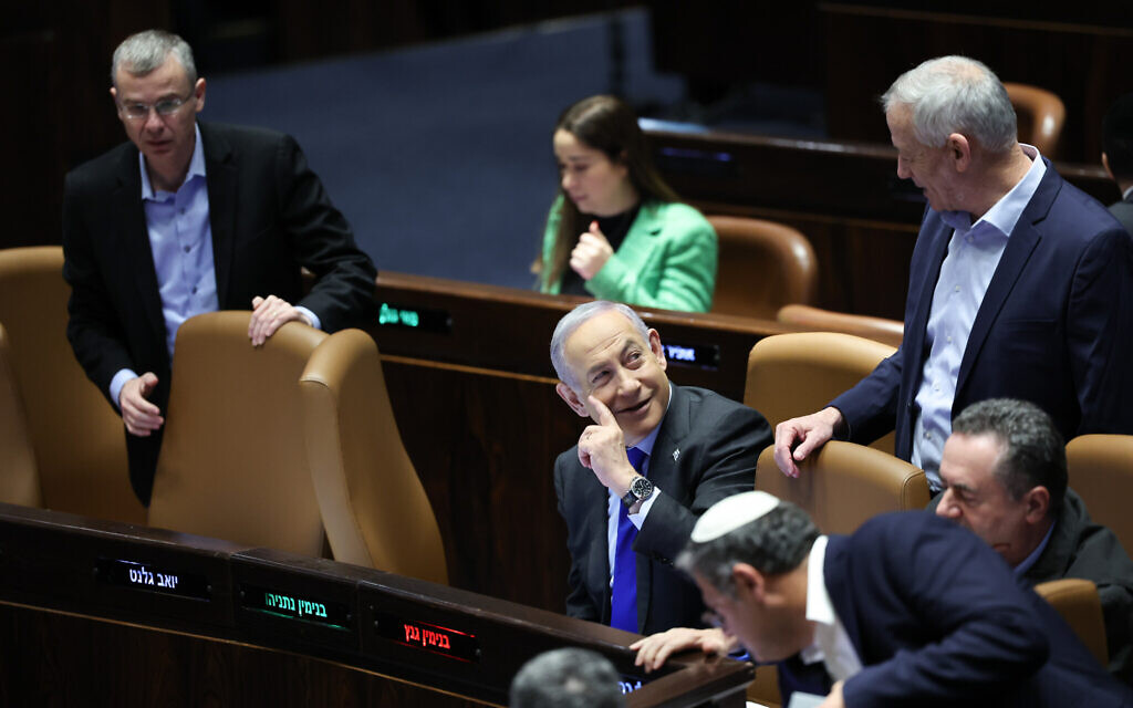 Prime Minister Benjamin Netanyahu, center, speaks to war cabinet minister Benny Gantz during a discussion and vote on the updated state budget at the Knesset plenum in Jerusalem, December 14, 2023. (Yonatan Sindel/Flash90)