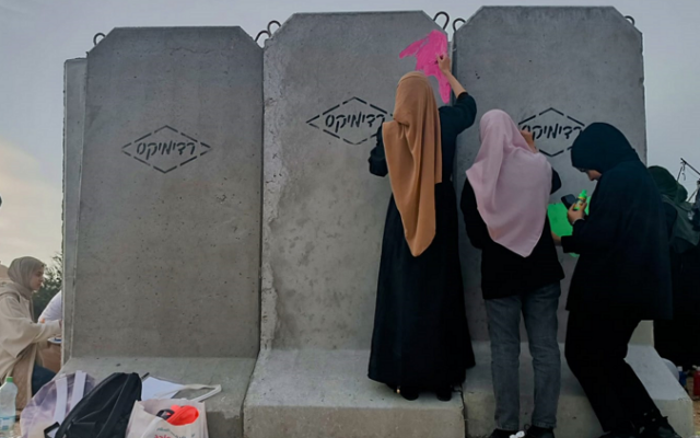 Bedouin volunteers paint a concrete rocket shelter installed the day before in the unrecognized Bedouin village of Umm al-Khiran, southern Israel, on December 7, 2023 (Gianluca Pacchiani / Times of Israel)