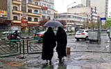 Illustrative: Women share an umbrella as they stand at Enghelab Square in Iran's capital Tehran on December 5, 2022.
(Atta Kenare/AFP)