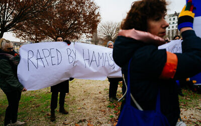 Demonstrators hold a banner reading 'Raped by Hamas' during a rally in front of UNESCO headquarters in Paris on December 1, 2023. (Dimitar DILKOFF / AFP)