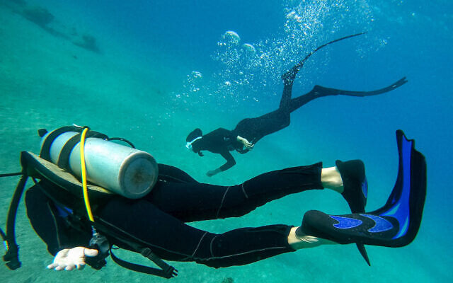 This underwater photograph taken on December 26, 2023, shows Yamit Avital and her husband Benny, who are among the survivors from Kibbutz Nir Oz, taking part in a free diving session offered to evacuated Israelis and survivors of the October 7 Hamas attacks, off the coast of Eilat. (Photo by Ilan Ben Zion/AFP)