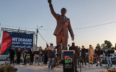 A statue of the late South African president Nelson Mandela stands in a street as members of the Ramallah-based Al-Kamandjati orchestra rehearse ahead of a ceremony organized to mark a landmark 'genocide' case filed by South Africa against Israel at the International Court of Justice, on January 10, 2024. (Photo by Marco Longari / AFP)