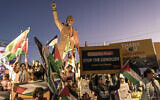 People raise flags and placards as they gather around a statue of late South African president Nelson Mandela to celebrate a landmark 'genocide' case filed by South Africa against Israel at the International Court of Justice, in the West Bank city of Ramallah on January 10, 2024. (Marco Longari/AFP)