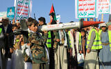 A Yemeni youth holds a mock rocket during a protest following US and British forces strikes, in the Houthi-controlled capital Sanaa on January 12, 2024. (MOHAMMED HUWAIS / AFP)