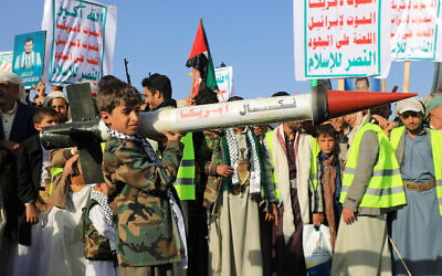 Illustrative: A Yemeni youth holds a mockup rocket during a protest following US and British strikes, in the Houthi-controlled capital Sanaa on January 12, 2024. Behind him, people hold up signs with the Iran-backed rebel group's slogan, 'God is great, death to America, death to Israel, curse on the Jews, victory for Islam.' (Mohammed Huwais/AFP)