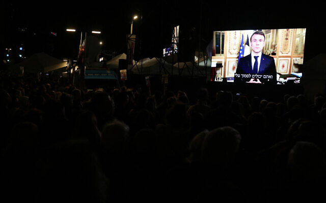 French President Emmanuel Macron is seen on a giant screen as he addresses a rally for the hostages in Tel Aviv on January 13, 2024. (AHMAD GHARABLI / AFP)