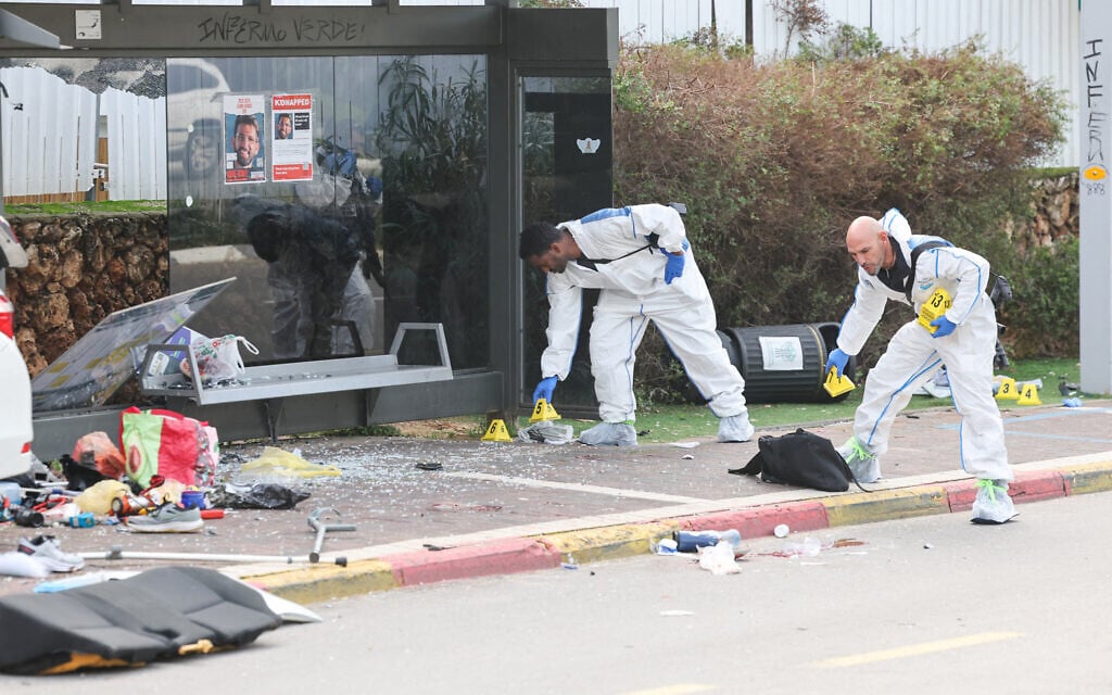 Israeli police forensics personnel inspect the area around a damaged car following a terrorist ramming attack in the central town of Ra'anana, on January 15, 2024. (JACK GUEZ / AFP)