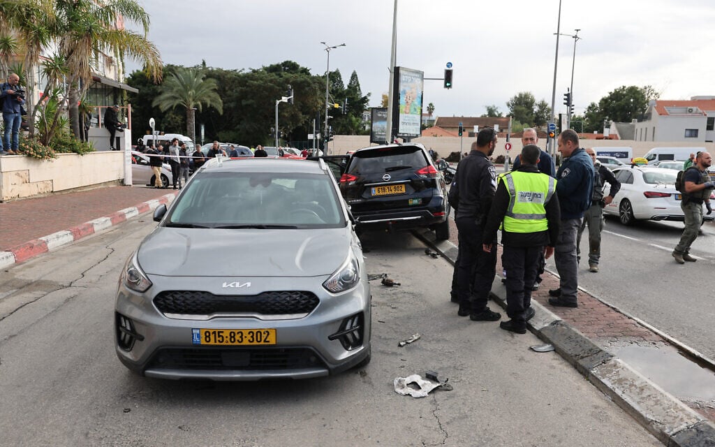 Israeli emergency and security personnel stand next to a damaged car following a terrorist ramming attack in the central town of Ra'anana, on January 15, 2024. (JACK GUEZ / AFP)