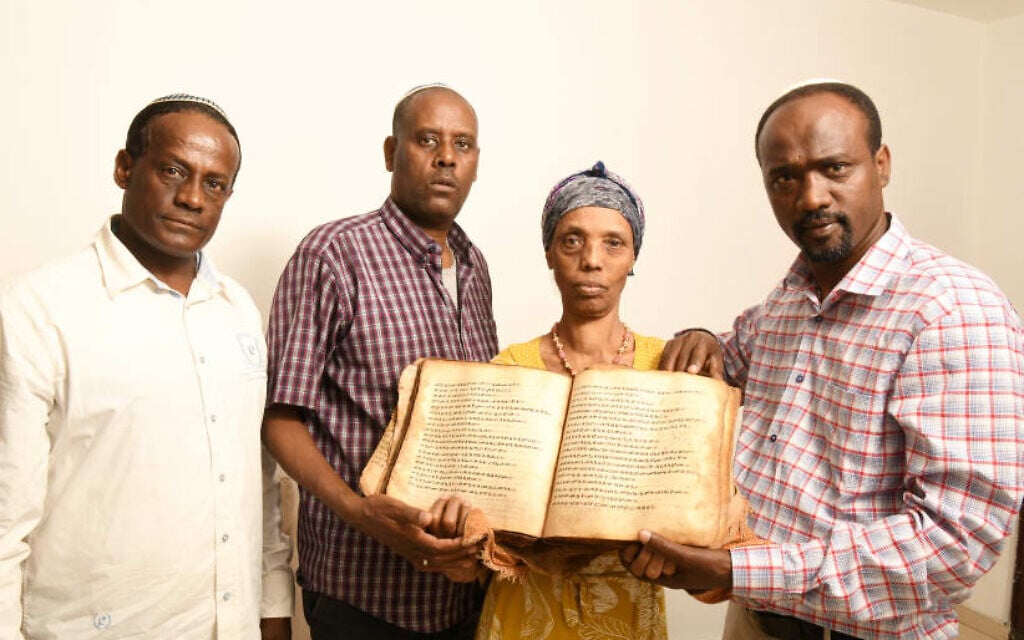 Ayanawo Ferada Senebato, right, and his family shown in Ashkelon, Israel, holding an ancient Orit book that they retrieved near Gondar, Ethiopia, in February 2022.
(Yossi Zeliger via JTA)