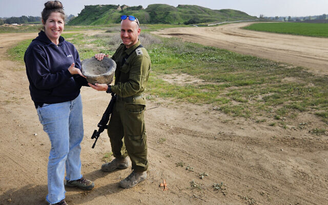 Lt. Col Yair Amitsur and Sarah Tal, both of the IAA, with a grain grinder discovered in a staging area near Gaza, in a photo released on December 7, 2024. (Ilan Glick/IAA)