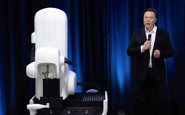 A video grab made from the online Neuralink livestream shows Elon Musk standing next to the surgical robot used to implant a device in the brain, seen during a Neuralink presentation on August 28, 2020. (Neuralink / AFP) A video grab made from the online Neuralink livestream shows Elon Musk standing next to the surgical robot used to implant a device in the brain, seen during a Neuralink presentation on August 28, 2020. (Neuralink / AFP)