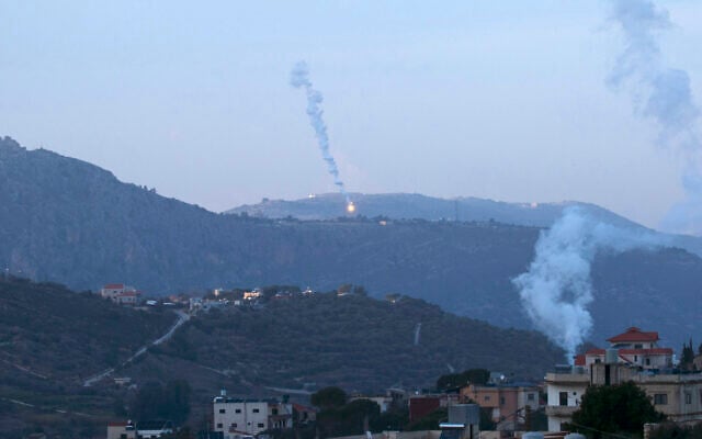 Smoke billows from a house hit in Israeli airstrikes as flares fall on the southern Lebanese village of Kfar Kila near the border with Israel on January 19, 2024. (Hasan Fneich/AFP)