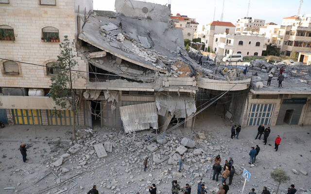 Palestinians gather near the rubble of a building destroyed during an Israel Defense Forces raid in Hebron in the West Bank on January 21, 2024 (MOSAB SHAWER / AFP)