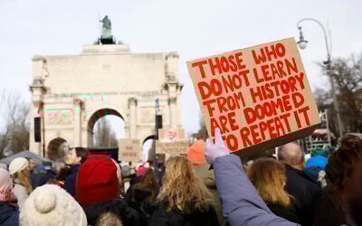 A participant holds up a placard with the lettering 'Those who do not learn from history are doomed to repeat it' during a demonstration against racism and far-right politics in front of the Siegestor (Victory Gate) memorial arch in Munich, southern Germany on January 21, 2024. (Photo by MICHAELA STACHE / AFP)