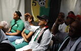 Residents react as they gather to watch the International Court of Justice (ICJ) ruling of the case against Israel brought by South Africa in The Hague at the Dullah Omar Centre in Cape Town, South Africa, on January 26, 2024, during an event organized by the South African ruling African National Congress party. (GIANLUIGI GUERCIA / AFP)