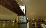 A Holocaust survivor's photo and quote projected on the Brooklyn Bridge, New York City, January 27, 2024. (Eugene Gologursky/Getty Images for LIVE2TELL By Gillian Laub/AFP)