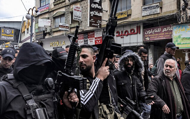 Gunmen march with mourners carrying the bodies of Palestinian terror operatives who were killed when undercover Israeli agents raided a hospital in Jenin, during their funeral in the northern West Bank city on January 30, 2024. (Zain Jaafar/AFP)