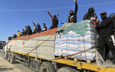Hamas members ride on top of a humanitarian aid truck in Rafah, Gaza Strip, December 19, 2023. (AP Photo)