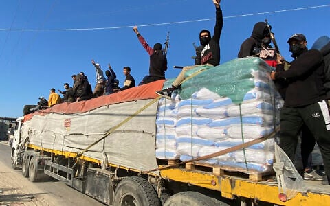 Hamas members ride on top of a humanitarian aid truck in Rafah, Gaza Strip, December 19, 2023. (AP Photo)
