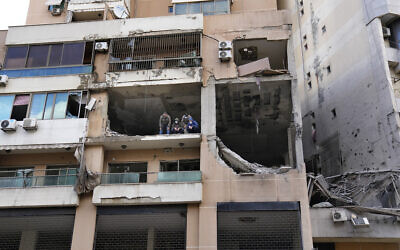 Investigators stand in an apartment building where an alleged Israeli strike killed top Hamas terror chief Saleh Arouri, in the southern suburb of Beirut, Lebanon, January 3, 2024. (AP/Hussein Malla)