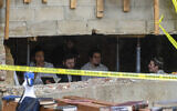 Hasidic Jewish students sit behind a breach in the wall of a synagogue that led to a tunnel dug by the students, Monday, Jan. 8, 2024, at Chabad-Lubavitch headquarters in New York. A group of Hasidic Jewish worshippers were arrested amid a dispute over a secret tunnel built beneath a historic Brooklyn synagogue, setting off a brawl between police and those who tried to defend the makeshift passageway. (Bruce Schaff via AP)