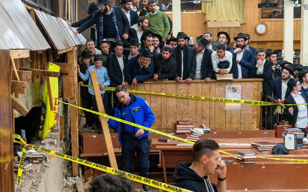 Hasidic Jewish students observe as law enforcement establishes a perimeter around a breached wall in the synagogue that led to a tunnel dug by students at Chabad-Lubavitch headquarters, January 8, 2024, in New York. (Bruce Schaff via AP) Hasidic Jewish students observe as law enforcement establishes a perimeter around a breached wall in the synagogue that led to a tunnel dug by students at Chabad-Lubavitch headquarters, January 8, 2024, in New York. (Bruce Schaff via AP)