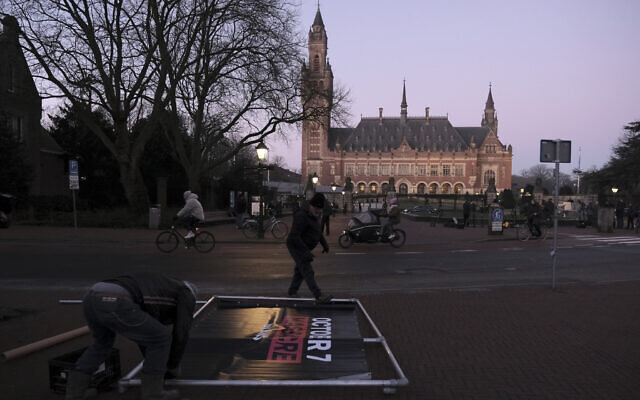 People prepare to install an 'October 7 massacre' banner outside the International Court of Justice prior to a hearing in The Hague, Netherlands, Jan. 11, 2024 (AP Photo/Patrick Post)