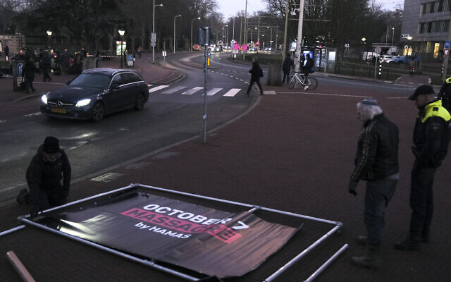 People prepare to install a banner outside the International Court of Justice prior to a hearing in The Hague, Netherlands, Thursday, Jan. 11, 2024. (AP Photo/Patrick Post)