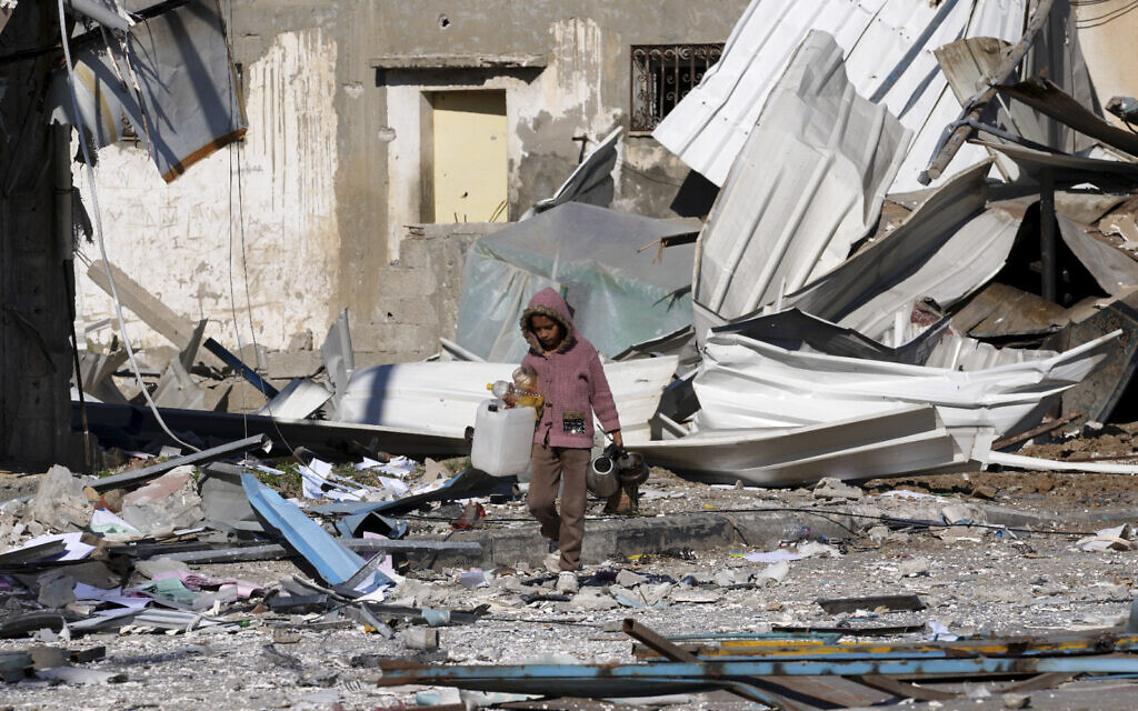 A Palestinian child walks past factories destroyed in the Israeli bombardment of the Gaza Strip in Deir al Balah on Saturday, January 13, 2024. (AP Photo/Adel Hana)