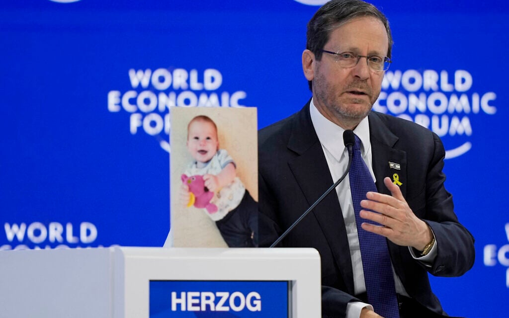 President Isaac Herzog speaks at the World Economic Forum in Davos, Switzerland, Jan. 18, 2024, alongside a photo of Hamas-held Israeli hostage Kfir Bibas. (AP Photo/Markus Schreiber)
