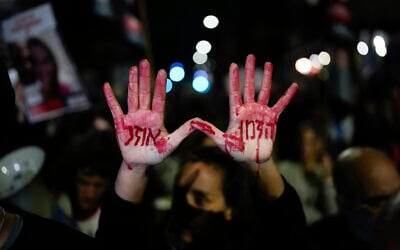 Relatives and supporters of the Israeli hostages held in the Gaza Strip by  Hamas attend a protest calling for their release outside the Knesset, in Jerusalem, Jan. 22, 2024. Hebrew on the hands with fake blood reads, 'Time is running out.' (AP Photo/Ohad Zwigenberg)