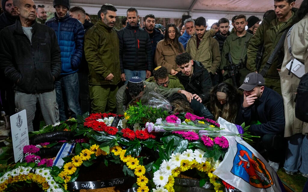 Family and friends of Israeli reservist Hadar Kapeluk mourn over his grave during his funeral at Mt. Herzl military cemetery in Jerusalem, Jan. 23, 2024 (AP Photo/Ohad Zwigenberg)