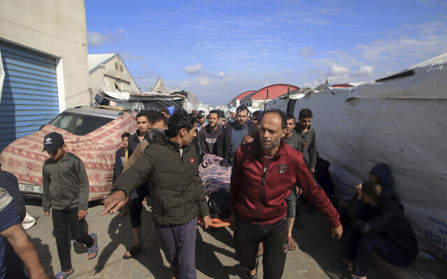 Palestinians carry a a body of a person killed in the strike of an UNRWA vocational training center, which displaced people use as a shelter in Khan Younis, southern Gaza Strip, Wednesday, Jan. 24, 2024. (AP Photo/Ramez Habboub)