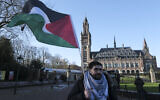A protester waving the Palestinian flag stands outside the Peace Palace, which houses the International Court of Justice, or World Court, in The Hague, Netherlands, January 26, 2024. (AP Photo/Patrick Post)