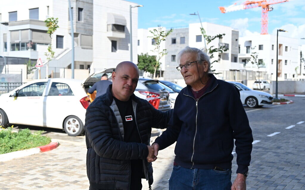 Ran Pauker, right, shakes hands with Mordi Israel in Kiryat Gat on January 3, 2024. (Canaan Lidor/Times of Israel)