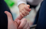 Illustrative photo of a newborn baby girl holding her mother's finger, Jerusalem, December 30, 2020. (Shir Torem/Flash90)